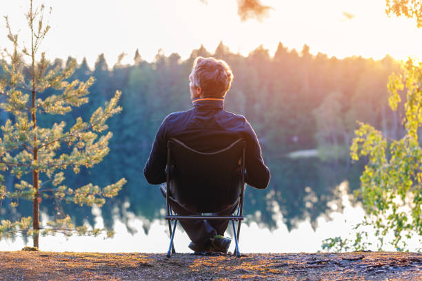 istock A man sits in a folding chair at sunset outdoor. 1338877350