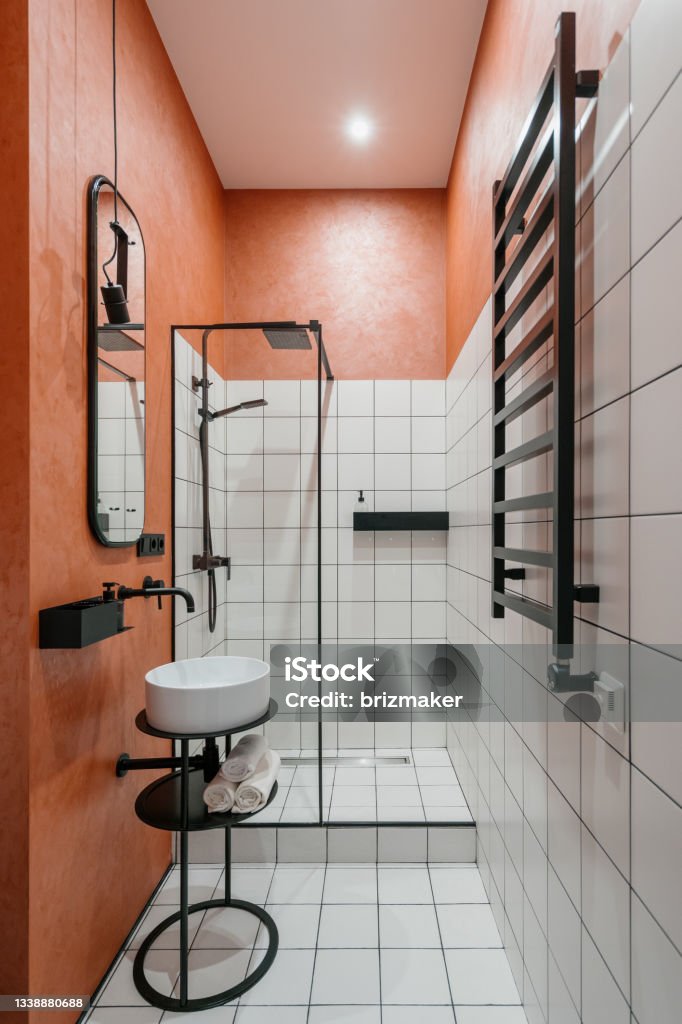 Modern bathroom interior, vertical shot of home design. Modern bathroom interior, vertical shot of home design. Contemporary apartment with minimalistic style shower, nobody at room with faucet, sink and mirror. Black modern furniture indoors. Bathroom Stock Photo