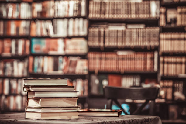 Pile of books on blurred background in bookstore or in library. Education, school, study, reading concept