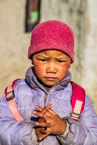 Tibetan little girl standing next to her parents house, small village in Upper Mustang. Mustang region is the former Kingdom of Lo and now part of Nepal,  in the north-central part of that country, bordering the People's Republic of China on the Tibetan plateau between the Nepalese provinces of Dolpo and Manang.