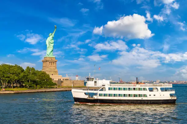 Statue of Liberty and tourist ship ferry in New York City, NY, USA