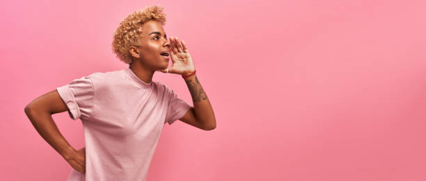 istock Horizontal panoramic photo amazing beautiful dark-skinned lady draws attention to great cool event, concert, sale, discount message. Her arms hands help yell novelty, isolated pink background 1338882687