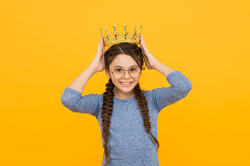 Shine the success. Happy child wear crown yellow background. Little beauty queen. Success and triumph. Pride and glory. Dreaming about success. Successful and ambitious. Success is the best revenge.