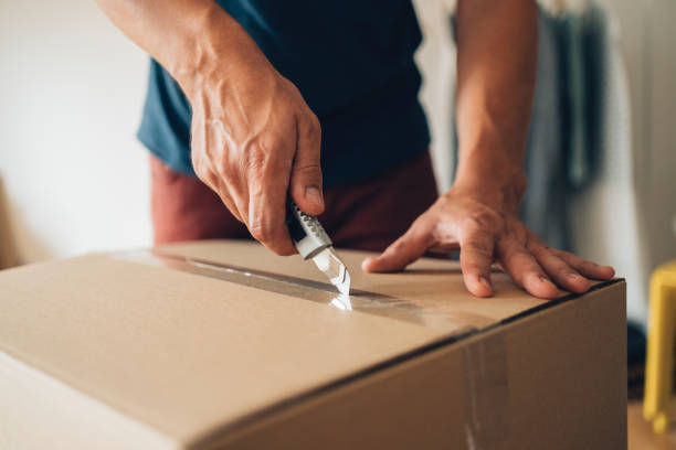 istock Moving In: An Anonymous Man Opening Cardboard Box with Scalpel 1338887389
