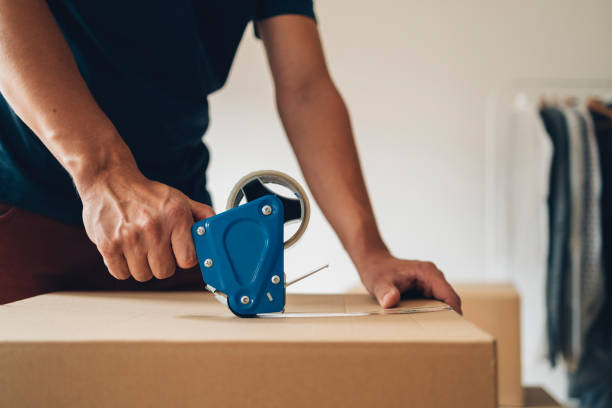 istock Moving In: Unrecognizable Man Packing a Carton Boxes with Adhesive Tape 1338887390