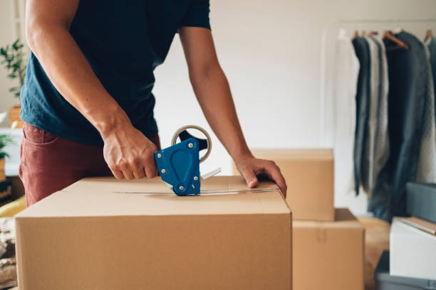 istock Moving In: Unrecognizable Man Packing a Carton Boxes with Adhesive Tape 1338887392
