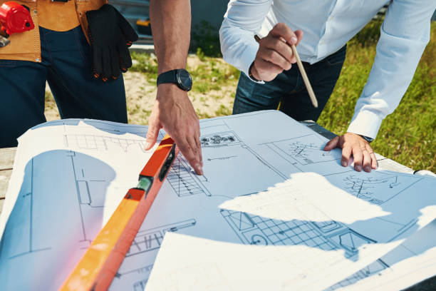 istock Two people examining house layout together outdoor 1338887739