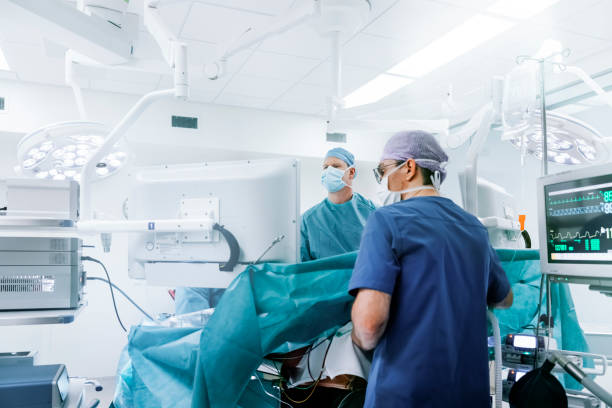 Medical team performing gastric bypass surgery Male surgeons performing laparoscopic surgery. Doctors are monitoring patient in operating room. They are in hospital. critical care photos stock pictures, royalty-free photos & images