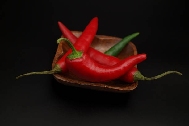 istock Chili peppers on wooden over a black background 1338889767
