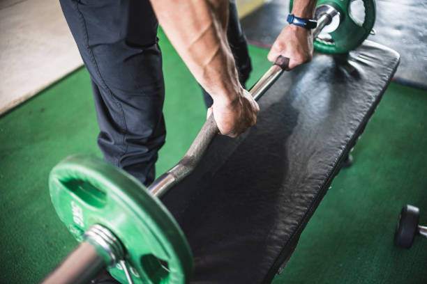 istock Two hands with bulging veins grab an EZ bar on a bench. Can represent the start of a workout set. 1338893080