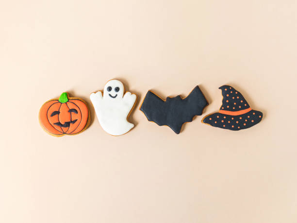 Various Halloween gingerbread cookies - Jack O'Lantern, ghost, bat and black hat on beige background.