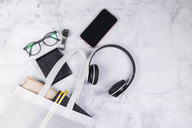 White women's leather bag with eyeglasses book and smart watch, phone, earphone, notepad.