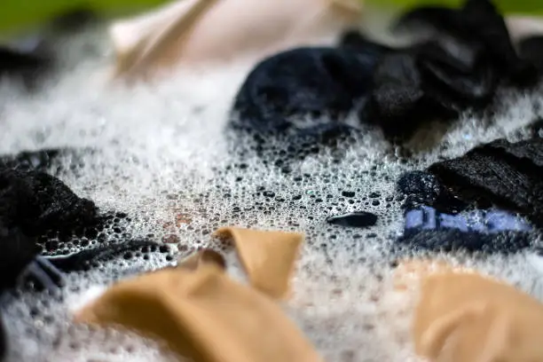 Photo of Washing clothes by hand with detergent bubble foam.