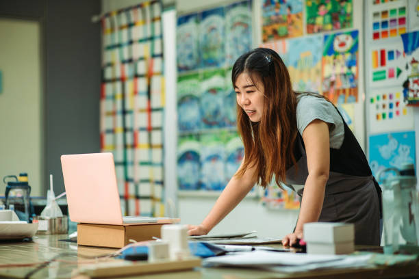 Asian chinese female smiling teacher teaching online art class at art school stock photo