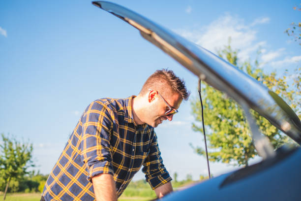 istock male driver smiling in front of a broken car 1338907036