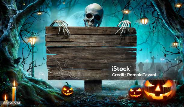 Halloween Party Card Pumpkins And Skeleton In Graveyard At Night With Wooden Board Stock Photo - Download Image Now