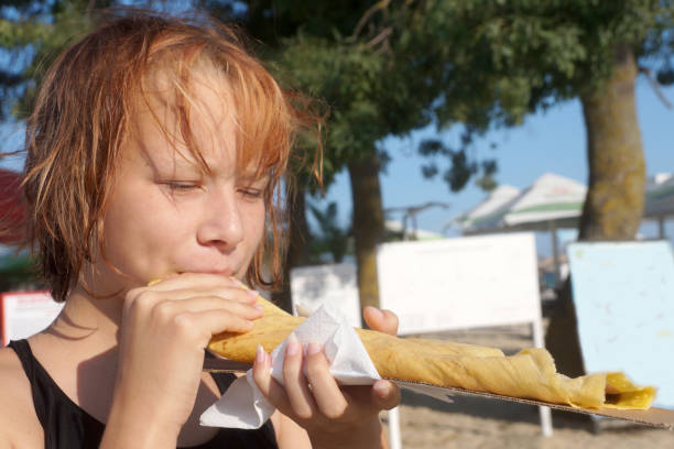 teen girl eating big pancake on the beach