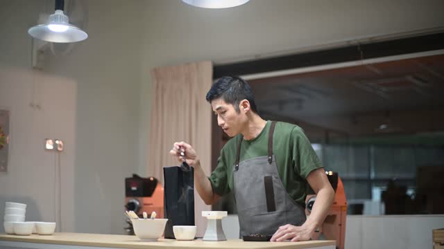professional male asian chinese barista preparing coffee cupping getting sample scooping weighing with weigh scale in a bright room