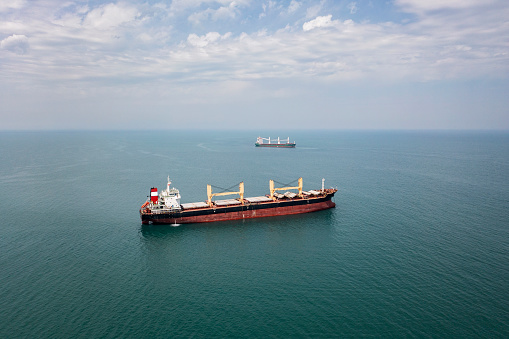 Cargo ships standing on the roadstead. Import, export and business logistic. International sea transportation concept. Aerial view of Black Sea against Samsun city in Turkey.
