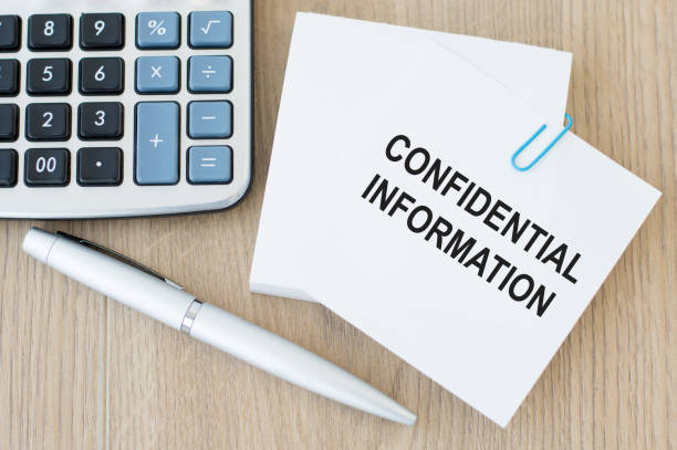 istock confidential information text on a white card that is pinned to note paper on a wooden table next to a pen and a calculator 1338911004