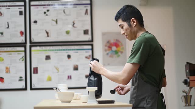 professional male asian chinese barista preparing coffee cupping getting sample scooping weighing with weigh scale in a bright room