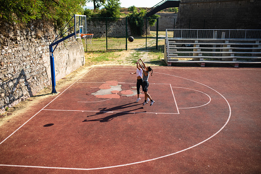 Two young women are playing streetball outdoors on a sunny day