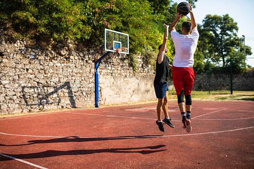 Two young men are playing streetball outdoors on a sunny day