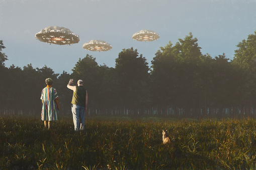 Senior couple waving at flying UFOs