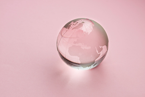 Earth crystal glass globe on pink background.