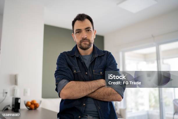 Portrait Of A Serious Man At Home Stock Photo - Download Image Now - Displeased, Anger, Arms Crossed