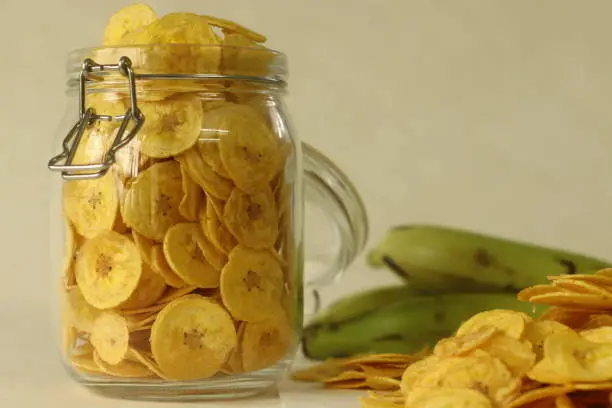 Fried banana chips made by deep frying under ripe banana slices. A main item of vegetarian Onam meals popularly called ethakka upperi. Shot on white background