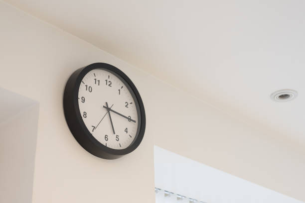 istock Wall clock with hands at quarter past five in white room 1338919852
