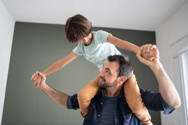 istock Father playing with son carrying him over the shoulder at home 1338920948
