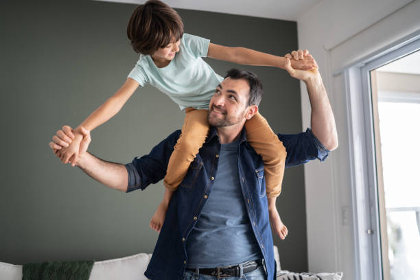 istock Father playing with son carrying him over the shoulder at home 1338921127