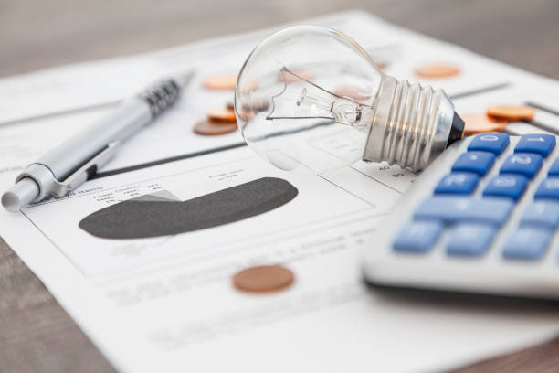 Light bulb on an electricity bill A light bulb, a pen, a calculator and some copper euro cent coins lie on top of an electricity bill. financial bill stock pictures, royalty-free photos & images