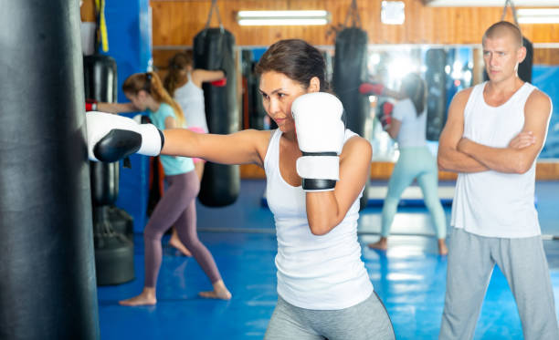 istock Asian female practicing punches with boxing bag at gym 1338921321