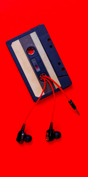istock Old audio cassette and wired vacuum headphones on a red background. 1338922014
