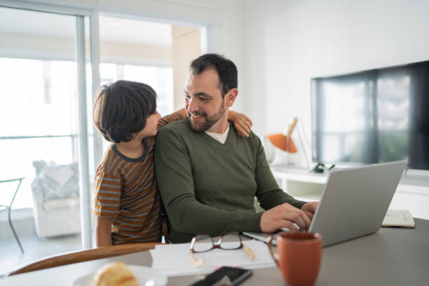 istock Father working using laptop and talking with son at home 1338922414