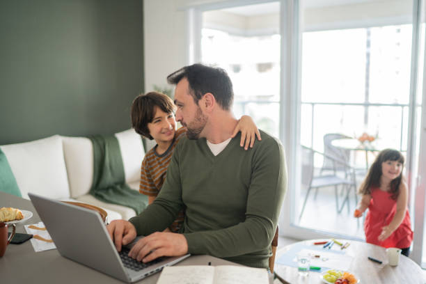 istock Father working using laptop and talking with son at home 1338922419