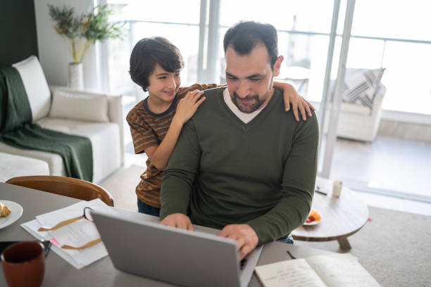 istock Father working using laptop and talking with son at home 1338922441