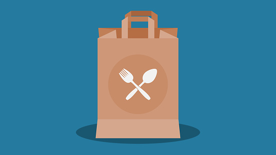 Takeout food, takeway food in brown paper bag. Spoon and fork figures on paper bag. Fast food delivery concept. Blue background.