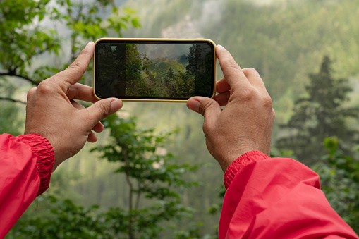 man taking photo with his mobile phone. Photographing the mountains and the forest