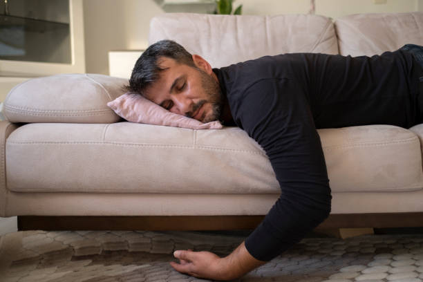 Man flopping down on sofa, needs rest at home