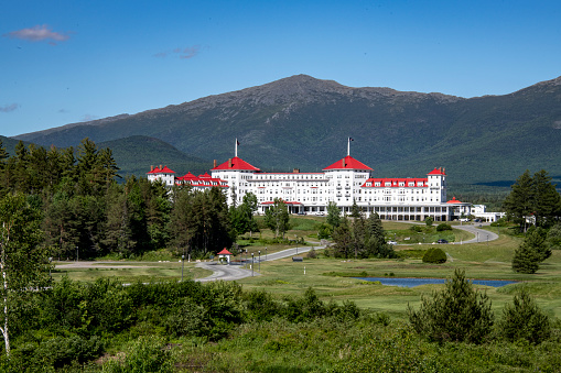 Originally Built in 1902, the hotel now operates as the Omni Mount Washington Hotel. It is located at the northern end of Crawford Notch and is one of the last surviving grand hotels in the White Mountains. It was extensively renovated in 1999. It is a National Historic Landmark.  It sits at the base of Mount Washington  (not visible in this photo). Mount Jefferson sits behind the hotel in this image.\nBretton Woods, New Hampshire\n06/17/2021