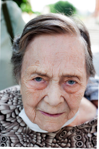 femme de plus de 80 ans avec un masque facial abaissé - senior adult 80 plus years aging process clothing photos et images de collection