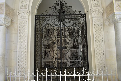 Part of the exterior of the Livadia Palace with white columns, arch and and metal wrought-iron gates. Livadia, Crimea, August 2021.