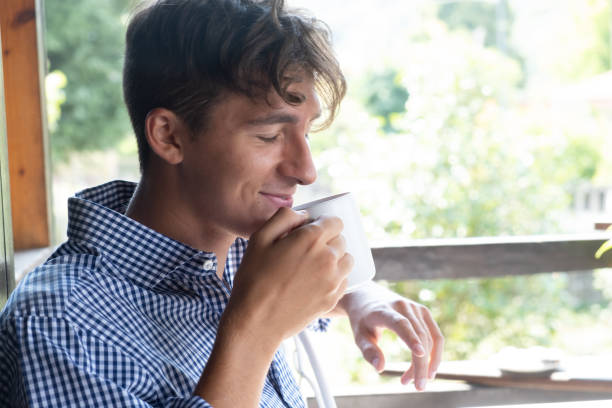 istock Young man smiling and sniffing cup of tea 1338930710