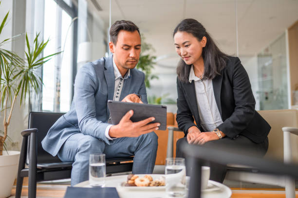 istock Two Asian Entrepreneurs Discussing Business in a Lobby 1338931692