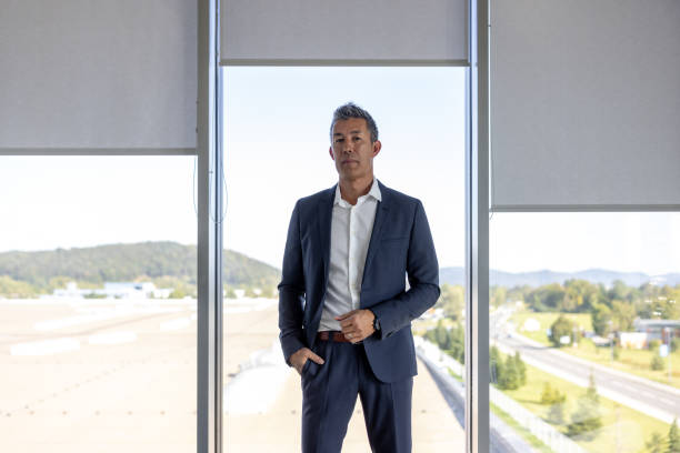 istock Confident Japanese-American executive standing in front of windows and looking at the camera 1338933021