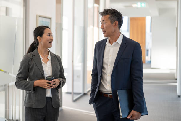 istock Japanese executives talking in an office hallway 1338933166